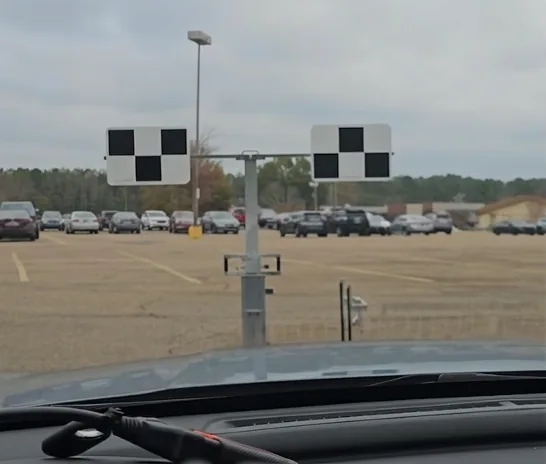 Two checkerboard calibration targets set up on a stand ahead of a vehicle, seen through the windscreen.